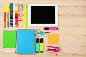 Digital tablet with stationery on wooden background