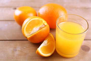 Glass of orange juice and slices on wooden table background