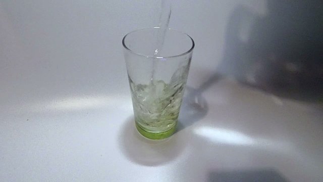 Slowmo pouring water on a glass on white background