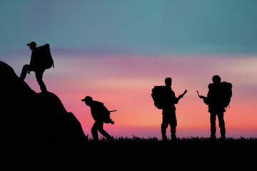 Hiker with backpack standing on a rock and enjoying sunset