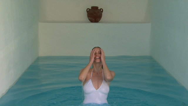 A woman emerging out of an indoor pool