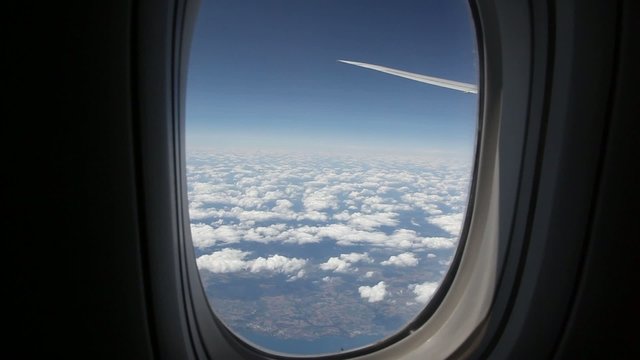 Clouds seen through the window of jet airplane. Airplane flies above the weather