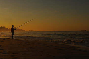 Silhouette man fishing on the beach