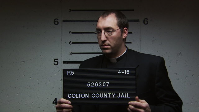 A priest being booked for a crime
