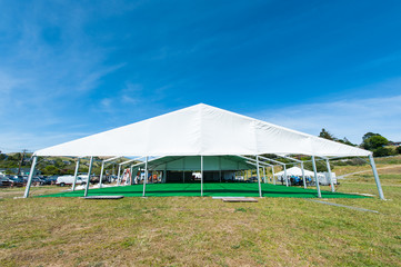 Huge white tent with green floor in field