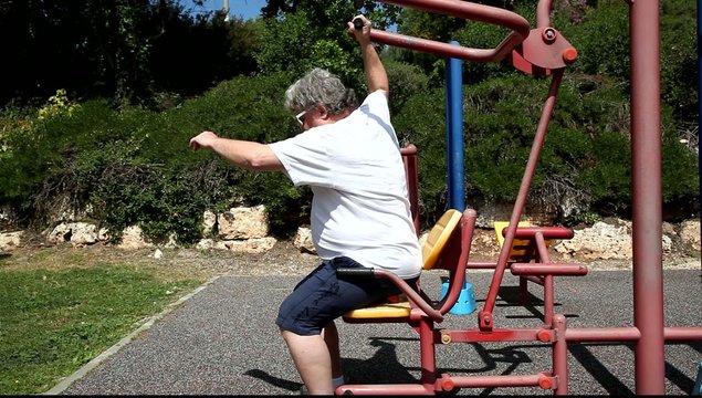 A big man with sunglasses works out in outdoor gym MRL