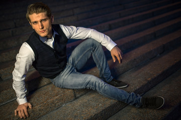 Handsome guy sitting on stairs.