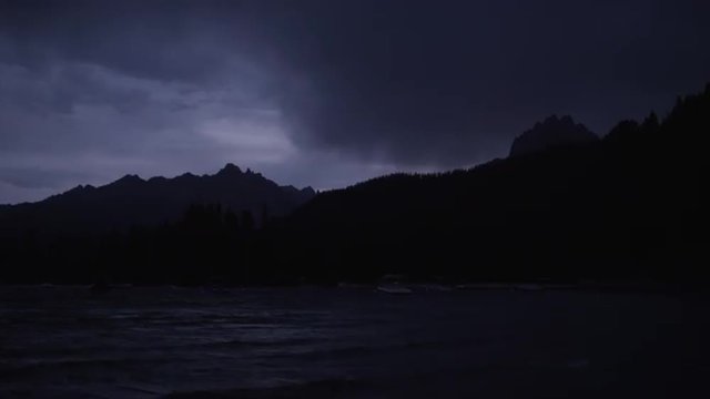 Wide shot of dark clouds over silhouetted mountain and lake / Redfish Lake, Idaho, United States