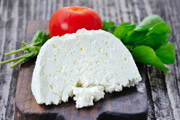 Cheese with tomatoes and onion on a wooden board
