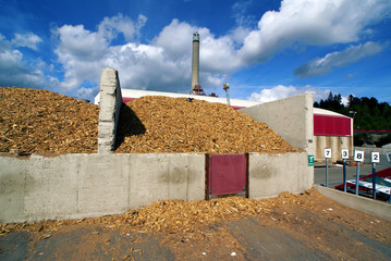 bio power plant with storage of wooden fuel against blue sky