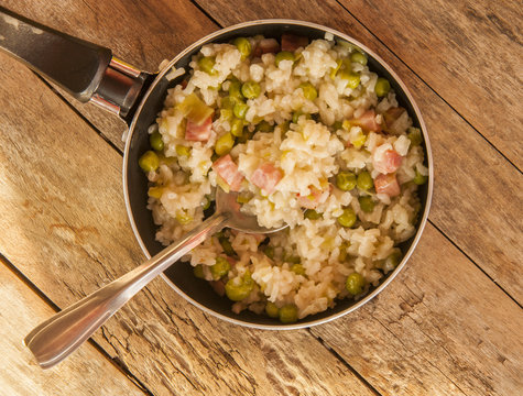 Lemon risotto with bacon and peas close up in pan