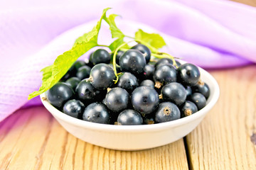 Black currants in bowl with napkin on board