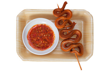 Grilled snake on skewer with chili sauce on white plate on mat
