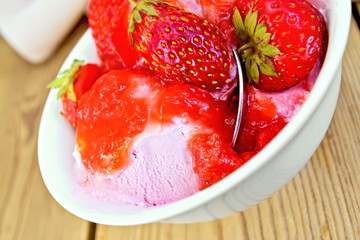 Ice cream strawberry in bowl with spoon on board
