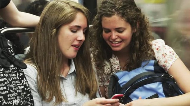 MS Two young women texting on subway train / Paris, France