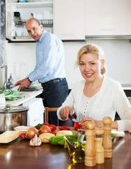 happy mature couple cooking Spaniard tomatoes