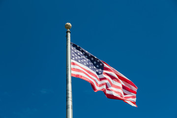 American Flag Flying from Silver Flagpole on Blue Sky