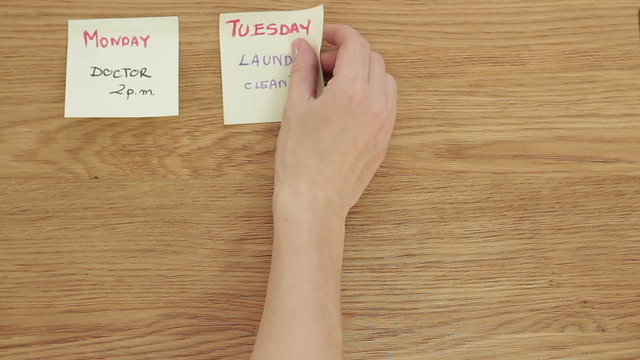 Woman's hand put post it papers with the days of the week