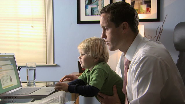 man with a child working on a notebook computer