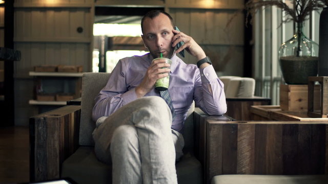 Businessman talking on cellphone and drinking cocktail