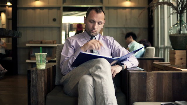 Young businessman working with documents sitting in cafe 
