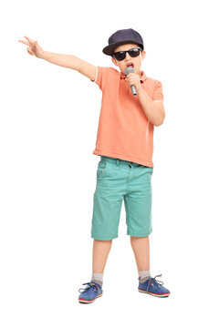 Little boy in hip hop outfit rapping on a microphone