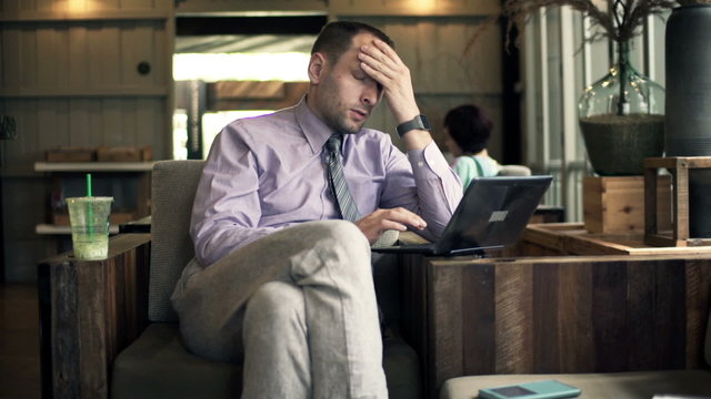 Young businessman having headache during work on laptop