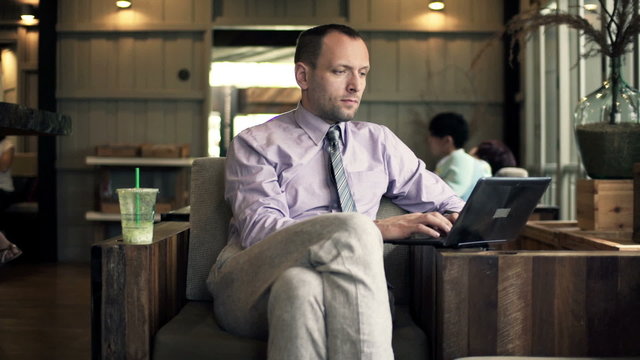 Handsome businessman working on laptop sitting in cafe 
