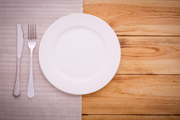 Empty plates, cutlery tablecloth on wooden table for dinner,