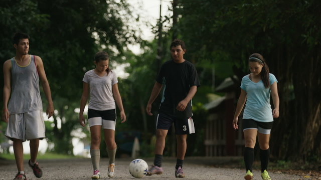 Wide panning shot of soccer team walking on dirt road / Esterillos, Puntarenas, Costa Rica