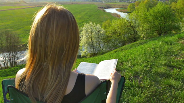 The woman read the book by picturesque landscape background. Real time capture