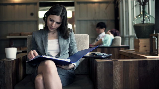Pretty, young businesswoman working with documents in cafe 
