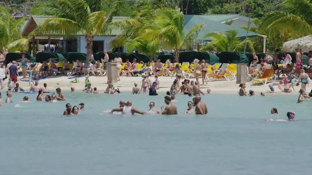 Panning shot of people enjoying the beach and ocean / Roatan, Honduras, Central America, 