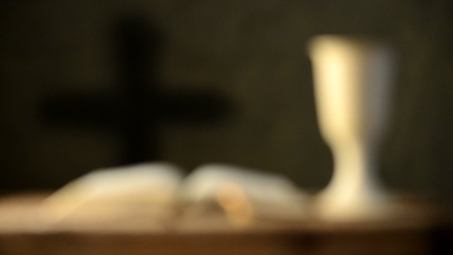 open bible with chalice and cross, shallow depth of field