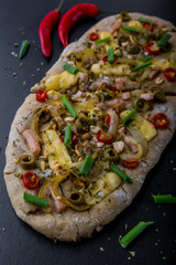 Focaccia with olives, peppers and chicken on a black board