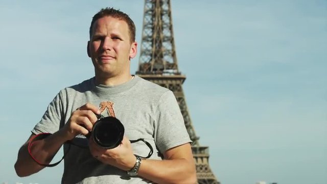 MS Young man taking pictures with Eiffel Tower behind / Paris, France