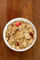 cereals with dry fruits in white bowl on brown background