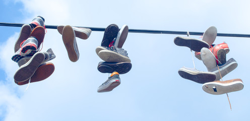 sport shoes are hanging over the thick wire.