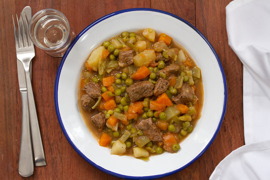 meat with carrot, peas and potato on white dish