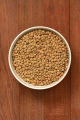dry lentil in bowl on brown background
