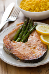 fried salmon with asparagus and lemon on white plate