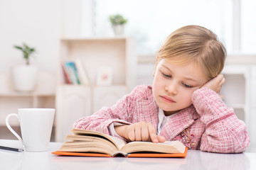 Little cute girl sadly reading book