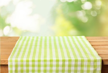 Abstract. Empty wooden table with tablecloth over bokeh