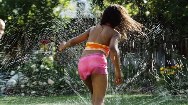children running in a sprinkler