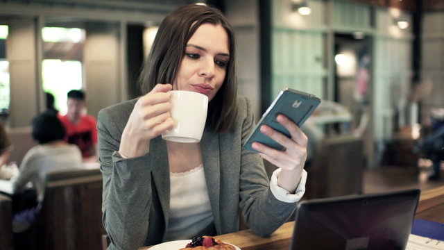 businesswoman using smartphone and drinking coffee in cafe