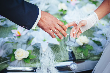 Obraz na płótnie Canvas hands of the bride and groom. wedding bouquet on black car