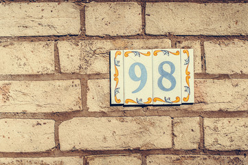 House number ninety eight on a brick wall.