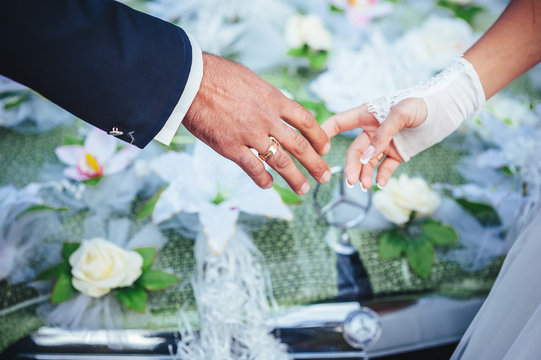 hands of the bride and groom. wedding bouquet on black car