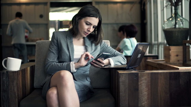 businesswoman with smartphone and laptop sitting in cafe 
