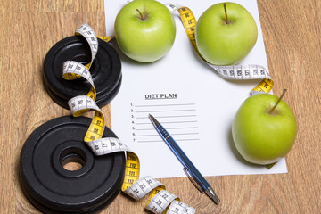 diet plan concept - apples, measure tape and dumbbell